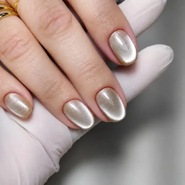 Unhas amendoadas curtas com esmaltação em gel dourada de efeito magnético