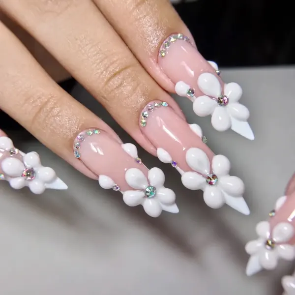 Unhas stiletto nude com flores 3D brancas