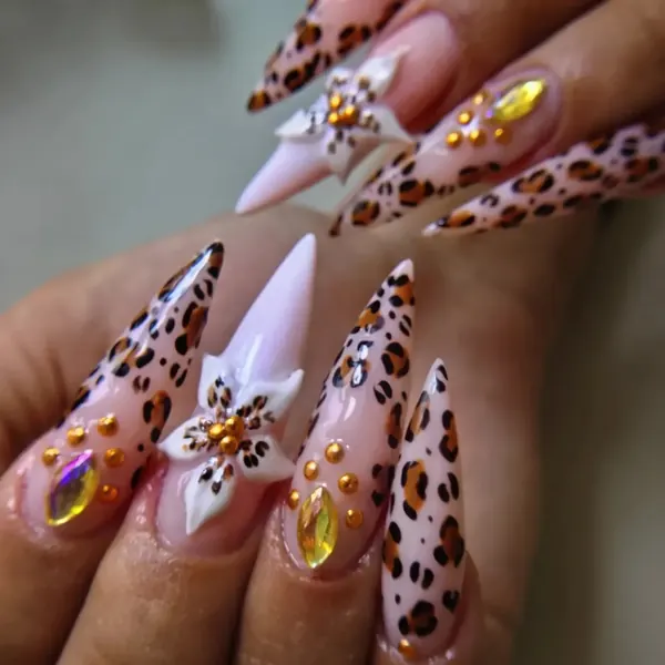 Unhas stiletto longas com estampa de oncinha, flor 3D e pedrarias douradas