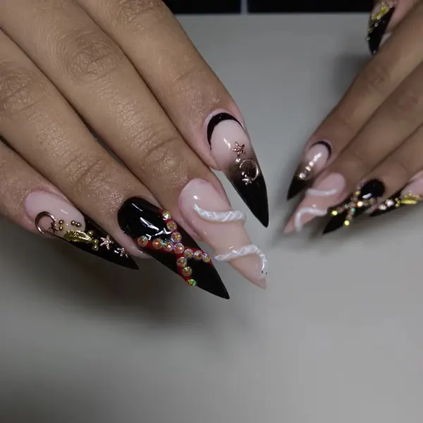 Unhas stiletto longas em preto e nude com nail art dourada e relevo
